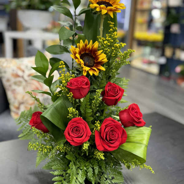 Tall arrangement of red roses and sunflowers with greenery