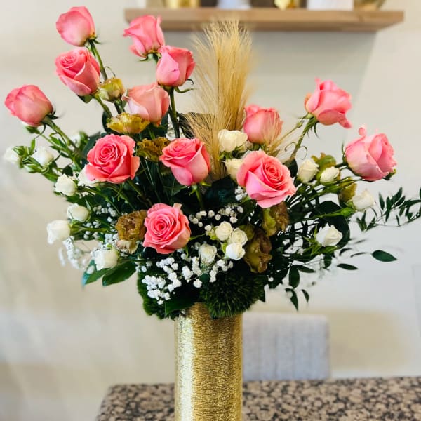 Pink and white roses arranged in a gold vase