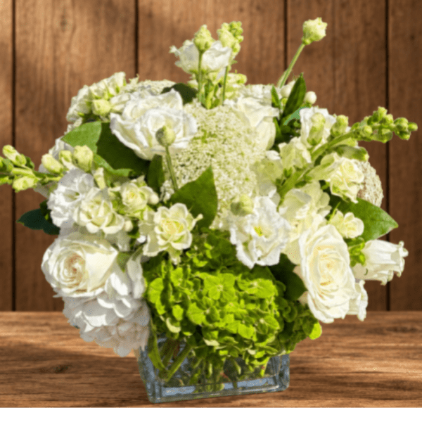 White roses and green hydrangeas in a clear glass vase