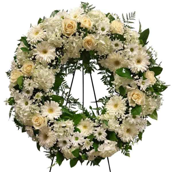 White floral wreath with roses, daisies, and hydrangeas on a stand