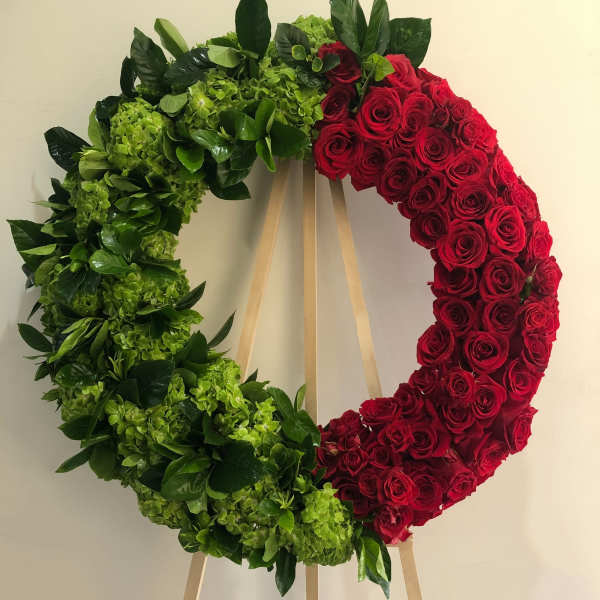 Heart-shaped wreath of red roses and green hydrangeas on an easel