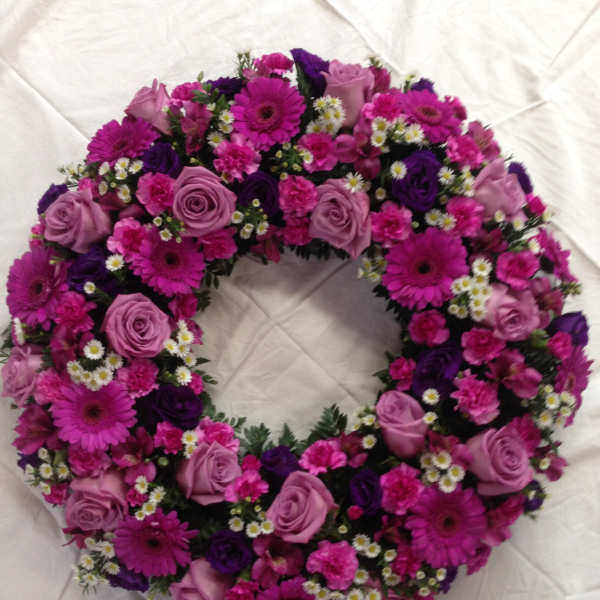 Circular wreath of pink and purple flowers on white fabric