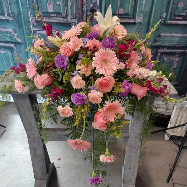 Large pink and purple floral arrangement on a wooden stand
