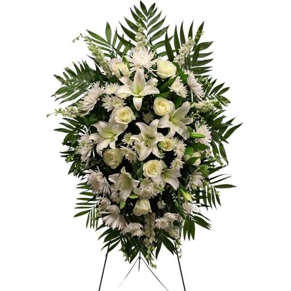 White floral standing spray with lilies, roses, and daisies on a stand