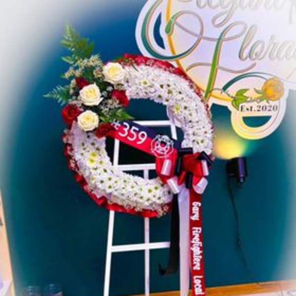 Standing floral wreath with red and white flowers on a white easel