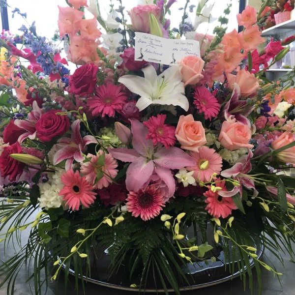 Large mixed flower arrangement with lilies, roses, and gerbera daisies in a low container