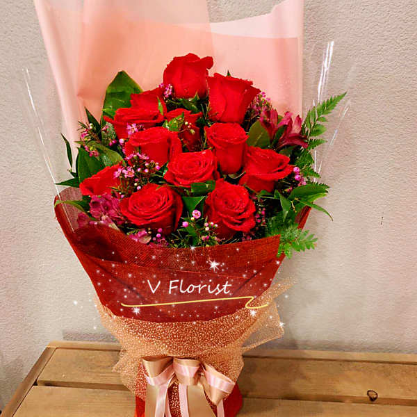 Bouquet of red roses wrapped in pink and red paper with a ribbon