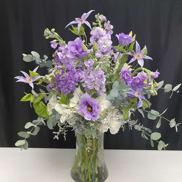 Purple and white bouquet in a clear glass vase