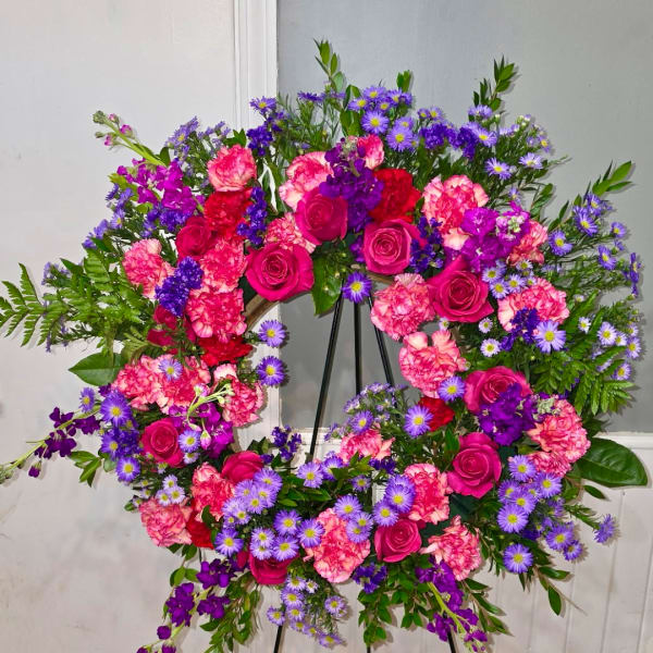 Heart-shaped floral wreath with pink roses, carnations, and purple daisies