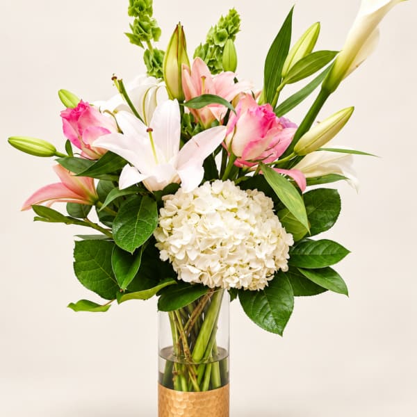 Pink and white lilies with hydrangea in a glass vase