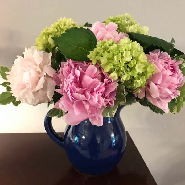 Pink and white peonies in a blue ceramic pitcher