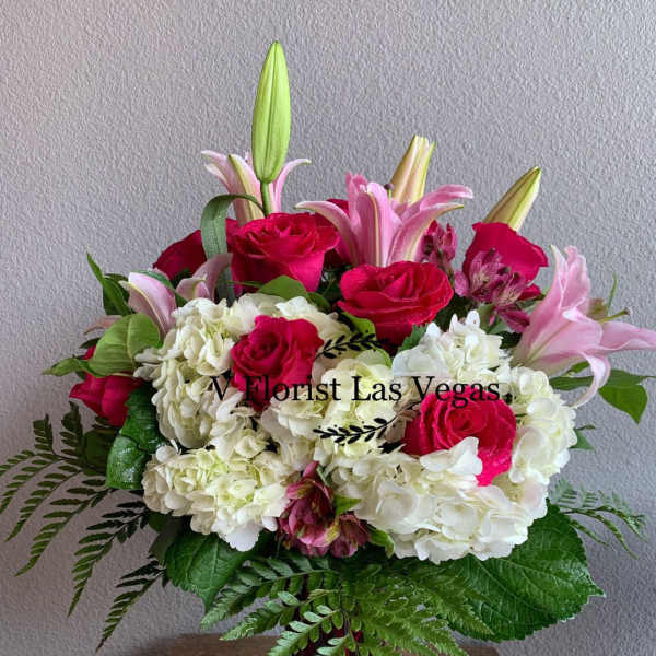 Pink roses and lilies with white hydrangeas in a red vase