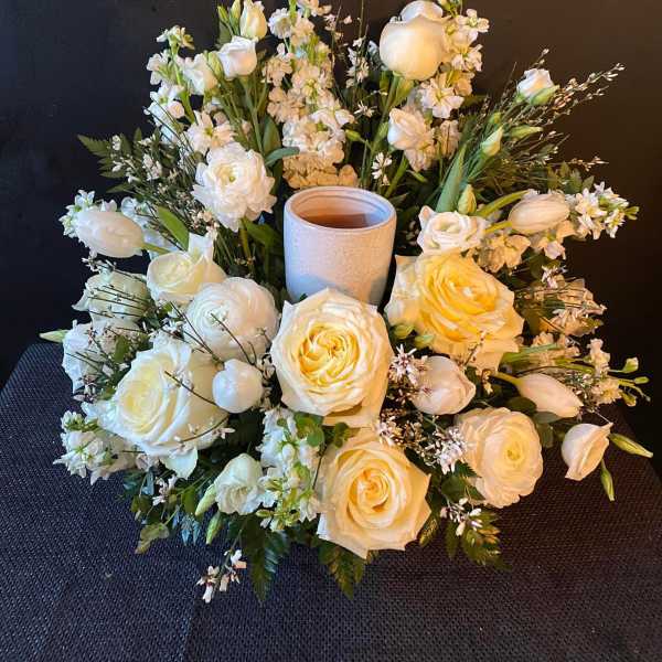 White floral arrangement with roses and tulips around a candle holder