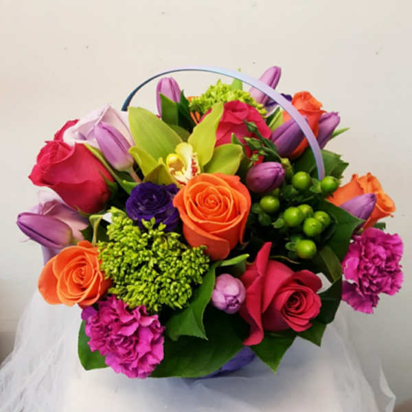 Colorful bouquet of roses, tulips, and orchids in a basket handle