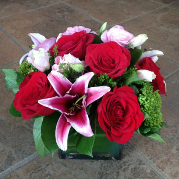 Red roses and pink lilies in a square glass vase