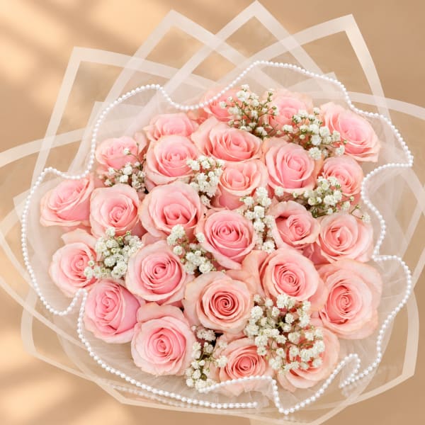 Bouquet of pink roses with white filler flowers wrapped in sheer paper