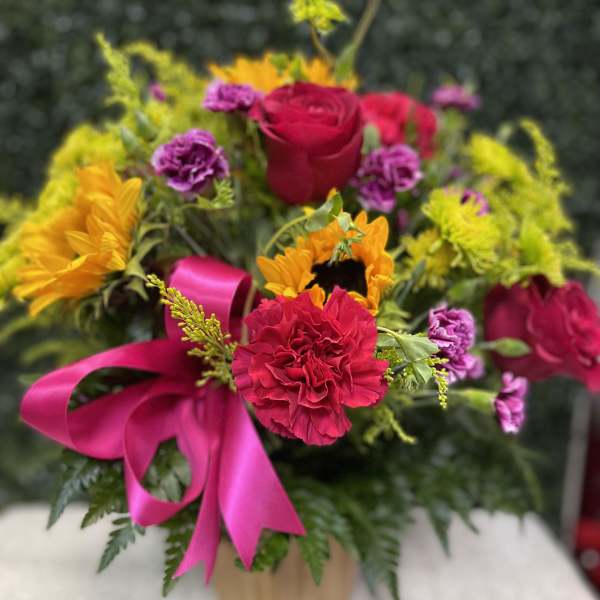 Bright mixed bouquet with roses, sunflowers, and carnations in a vase