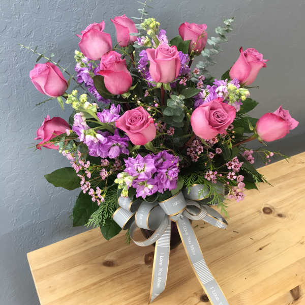 Pink roses and purple flowers in a vase with a ribbon bow