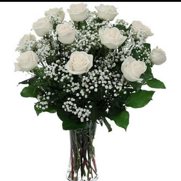 White roses and baby's breath in a clear glass vase