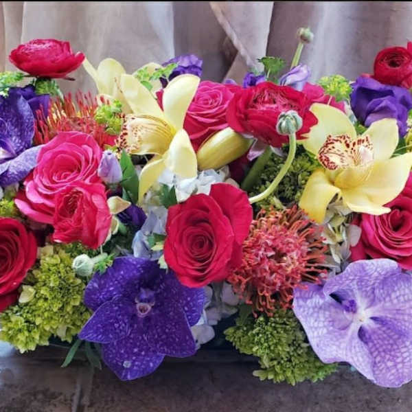 Colorful bouquet of roses, orchids, and lilies arranged low and wide