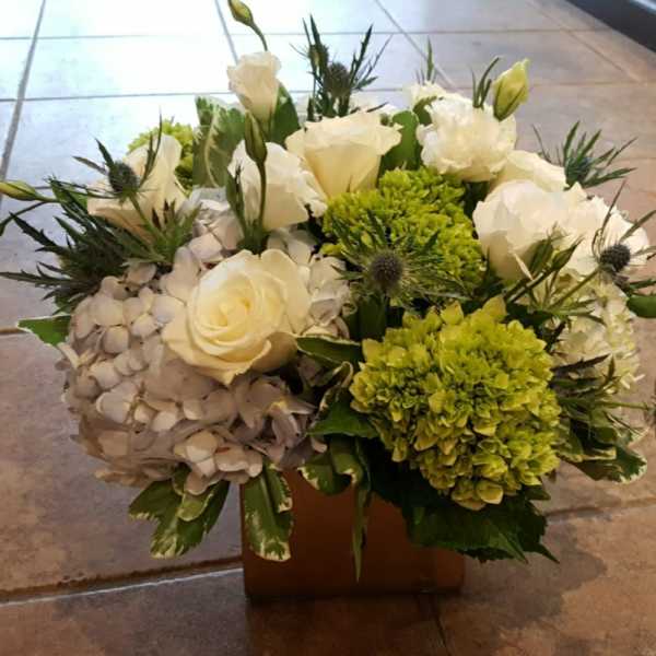 White roses and green hydrangeas in a low square container