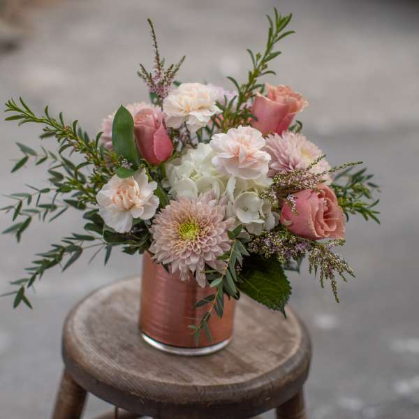 Pink and white bouquet in a copper vase on a stool