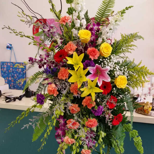 Tall mixed flower standing spray with lilies, roses, and orchids