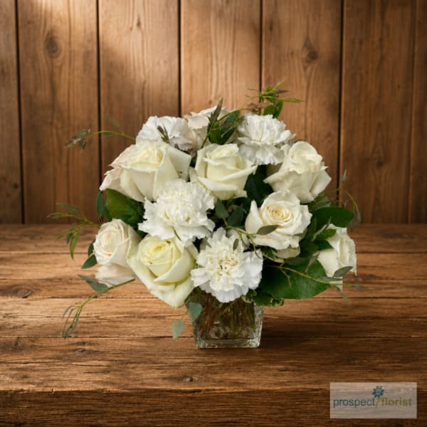 White rose and carnation bouquet in a clear glass vase