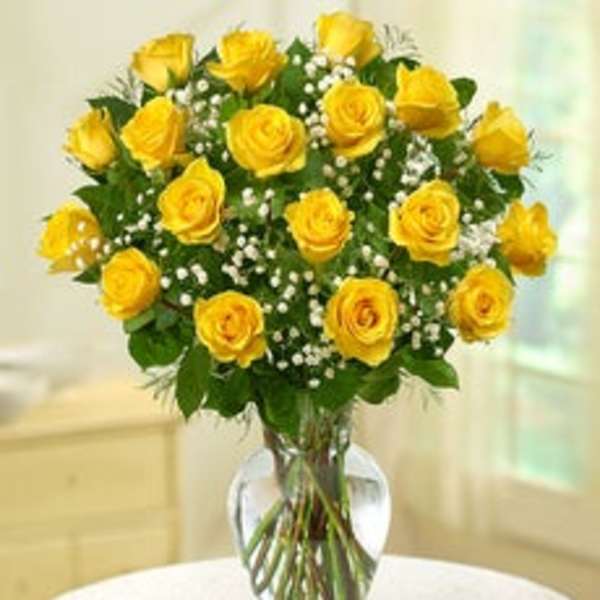 Yellow roses arranged in a clear glass vase with white filler flowers