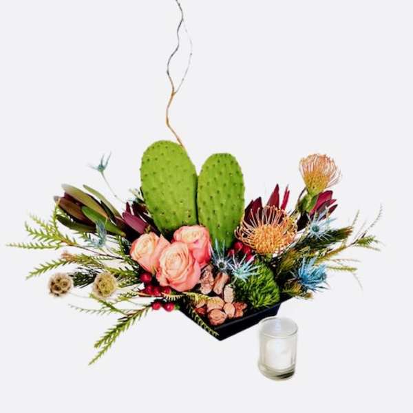 Floral arrangement with pink roses, protea, and cactus pads in a black container