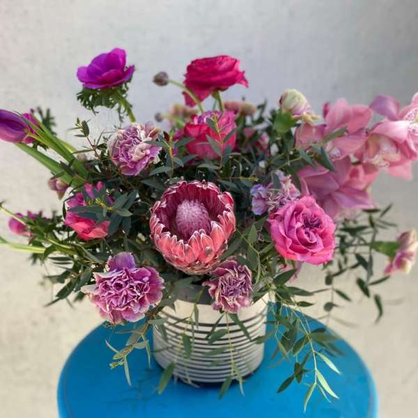 Pink and purple mixed bouquet in a striped container