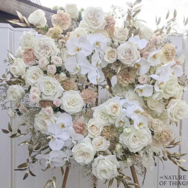 Large white floral arrangement with roses and orchids on an easel