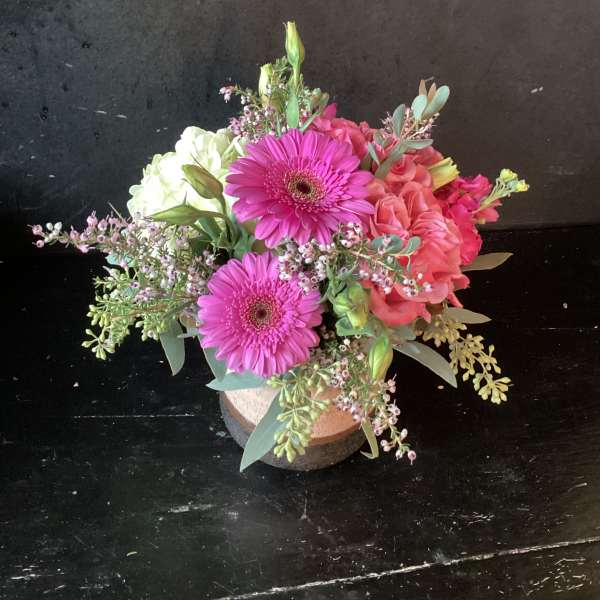 Bouquet of pink gerbera daisies and roses in a low round container