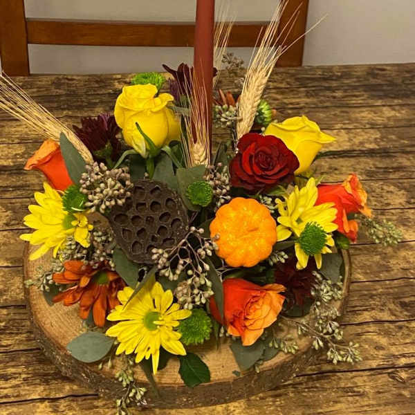 Autumn floral centerpiece with a tall candle in a wooden base