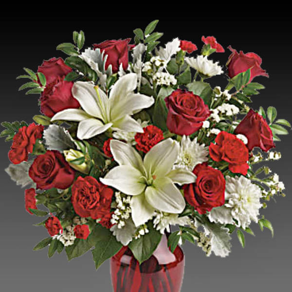 Red roses and white lilies arranged in a red glass vase