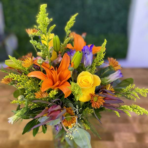 Mixed bouquet with orange lilies and yellow roses in a glass vase