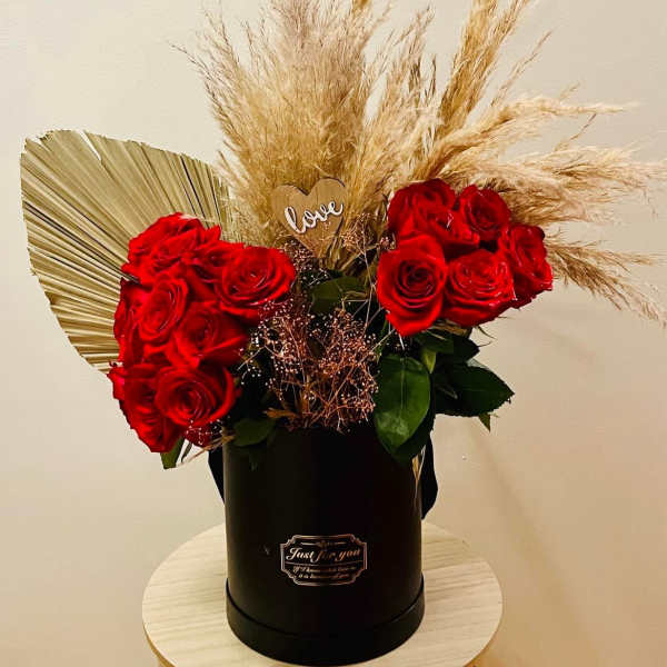 Red roses in a black hatbox with dried pampas grass and a small heart topper