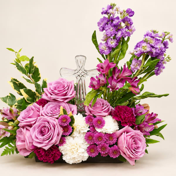 Pink and purple floral arrangement with a clear glass cross centerpiece