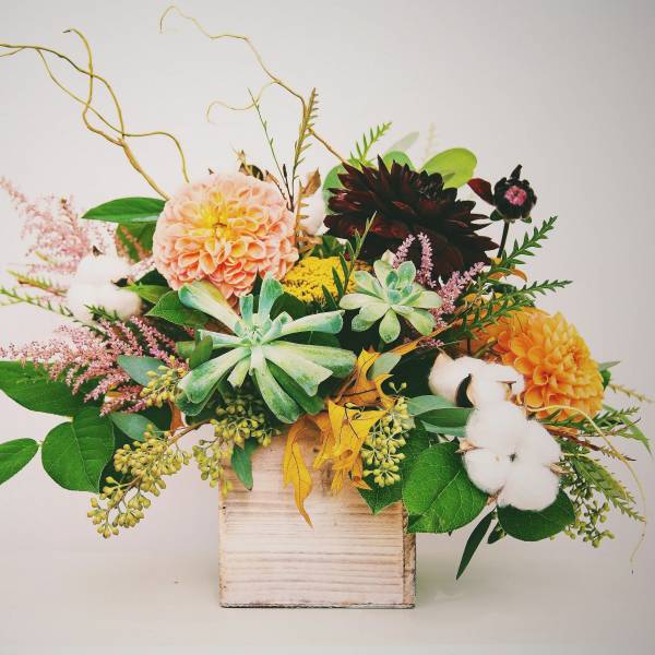 Mixed floral arrangement in a wooden box with succulents and cotton stems