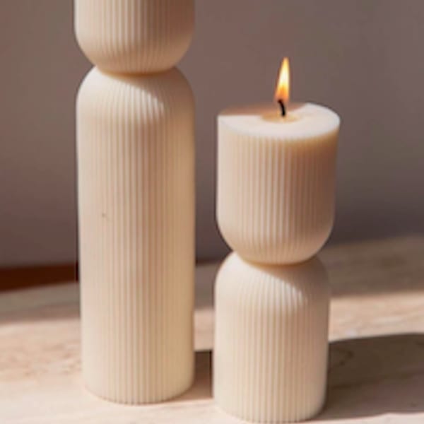 Two lit cream pillar candles with ribbed sides