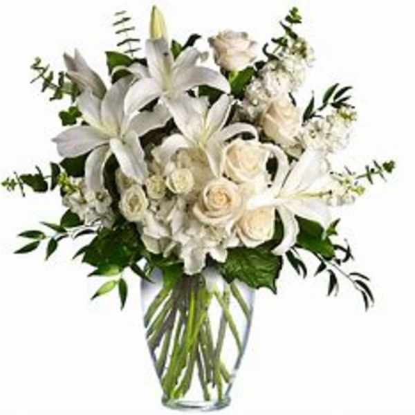 White lilies and roses arranged in a clear glass vase