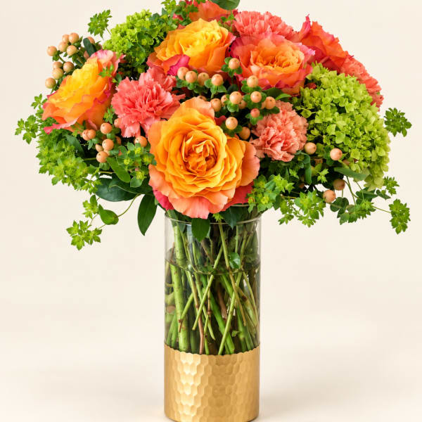Orange and coral roses with pink carnations in a glass vase