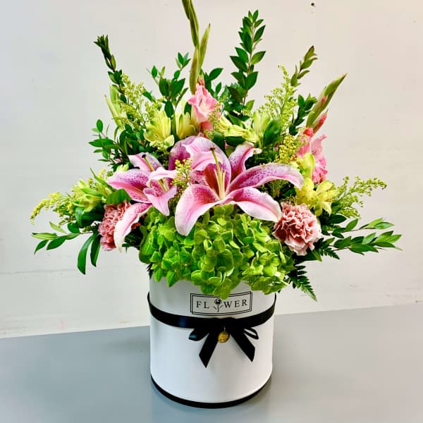 Pink lilies and green hydrangeas in a white hatbox