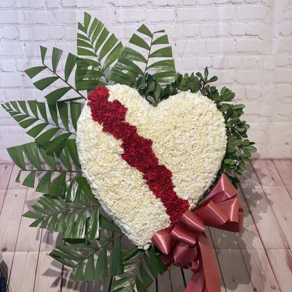 Heart-shaped floral tribute with a red diagonal stripe and pink ribbon