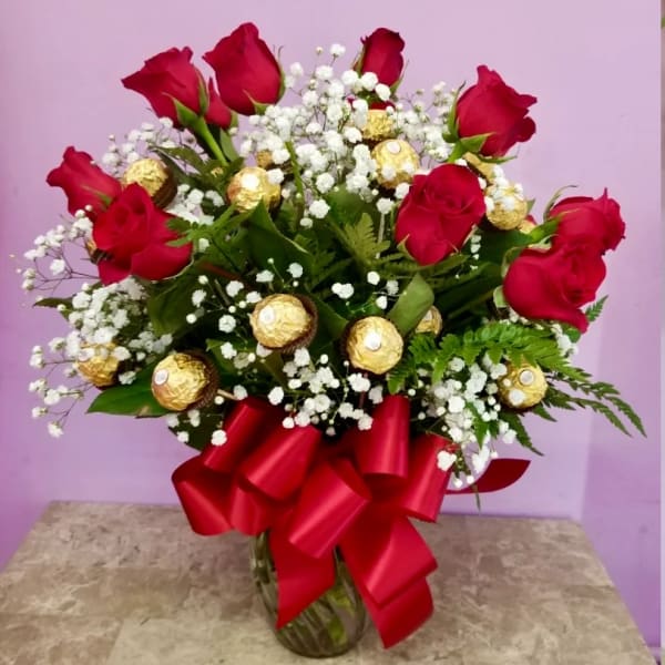 Red roses with white baby's breath in a glass vase with a red bow