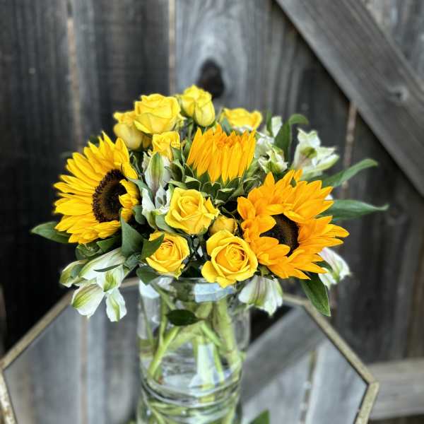 Yellow sunflowers and roses in a clear glass vase