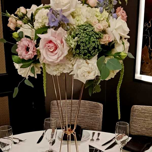 Tall floral centerpiece with pink and white roses on a gold stand
