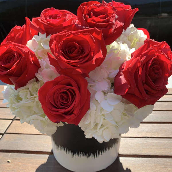 Red roses and white hydrangeas in a black-and-white vase