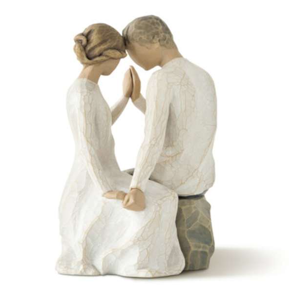 A carved figurine of a seated couple touching foreheads and hands.