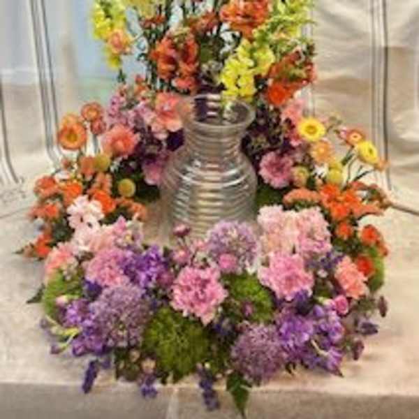 Large colorful floral arrangement around a silver vase